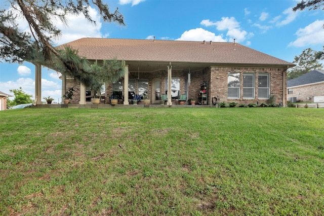 back of house with a shingled roof, a yard, and brick siding