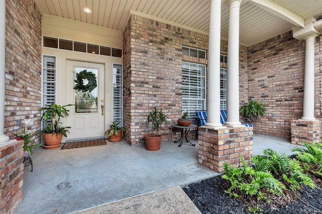entrance to property with covered porch and brick siding