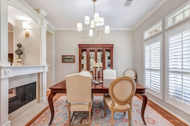 dining space featuring visible vents, ornamental molding, an inviting chandelier, baseboards, and a tiled fireplace