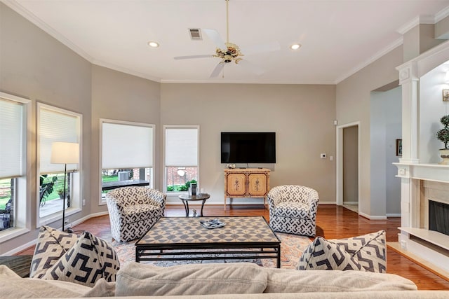 living area featuring crown molding, ceiling fan, baseboards, wood finished floors, and visible vents