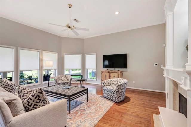 living area featuring visible vents, a ceiling fan, light wood-style flooring, and ornamental molding