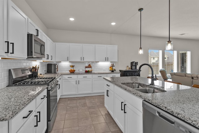 kitchen featuring white cabinets, hanging light fixtures, appliances with stainless steel finishes, a sink, and backsplash