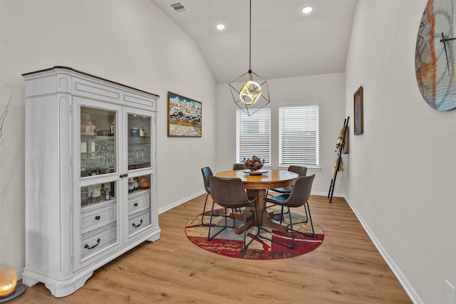 dining area with visible vents, baseboards, vaulted ceiling, and light wood-type flooring