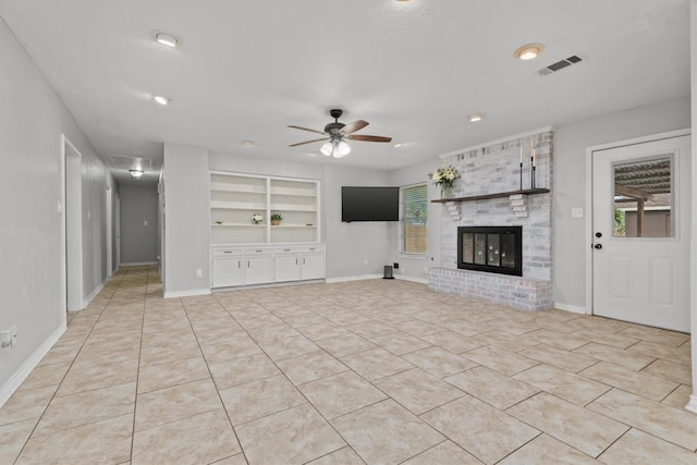 227 Oak Hollow St, Conroe, TX 77301 - unfurnished living room featuring a brick fireplace, ceiling fan, visible vents, and light tile patterned floors