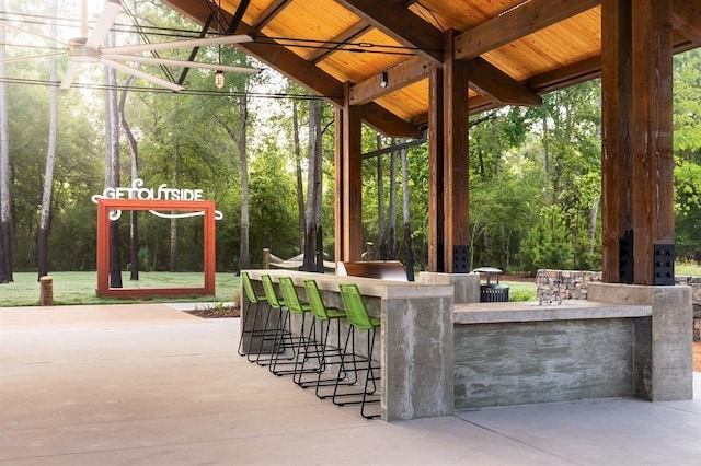 view of patio / terrace featuring outdoor dry bar and a view of trees