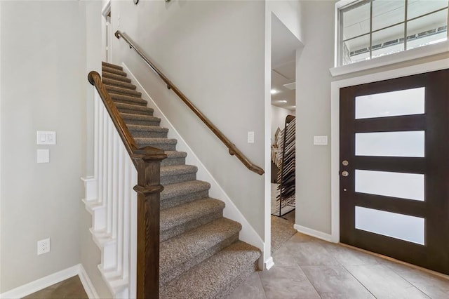 entryway with stairway, baseboards, a high ceiling, and light tile patterned flooring
