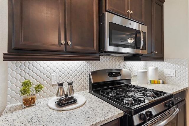 kitchen featuring decorative backsplash, appliances with stainless steel finishes, dark brown cabinets, and light stone countertops