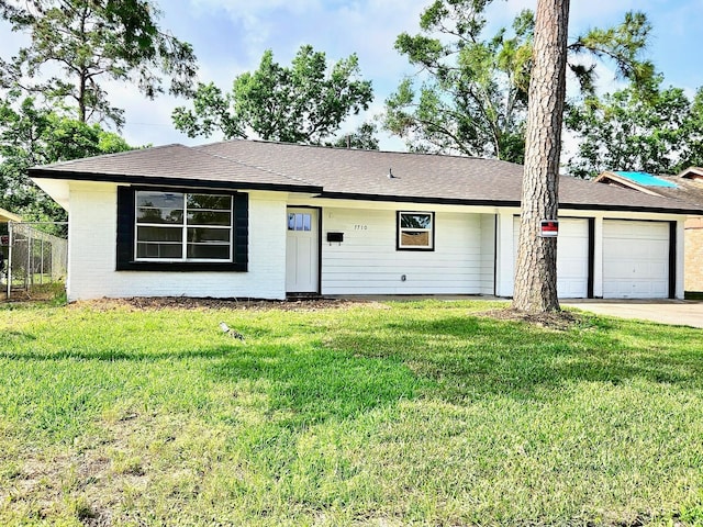 ranch-style house with fence, an attached garage, brick siding, a front yard, and driveway
