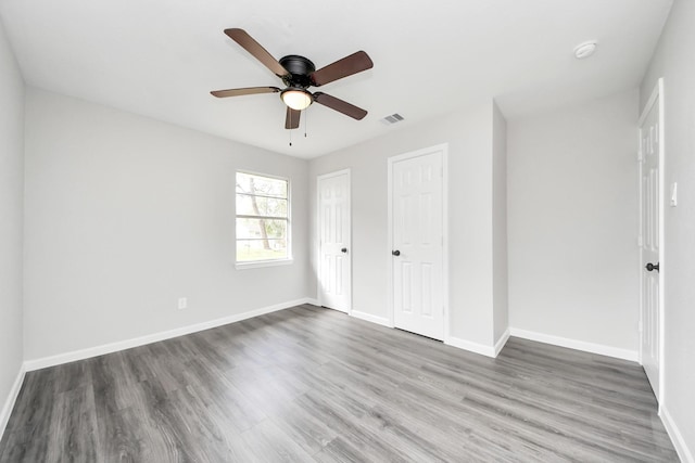 unfurnished bedroom featuring baseboards, a ceiling fan, wood finished floors, and visible vents