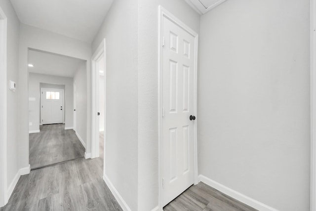 corridor with baseboards and wood finished floors