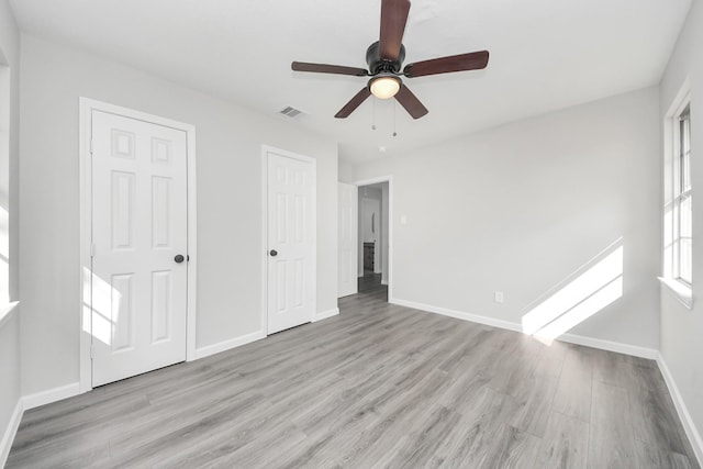 unfurnished bedroom featuring baseboards, visible vents, ceiling fan, and light wood finished floors
