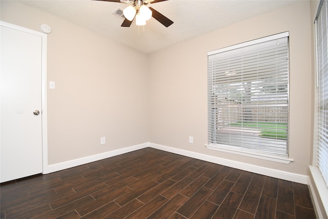 spare room with baseboards, ceiling fan, dark wood finished floors, and a textured ceiling