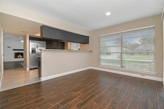 unfurnished living room featuring baseboards, a brick fireplace, and dark wood-style floors