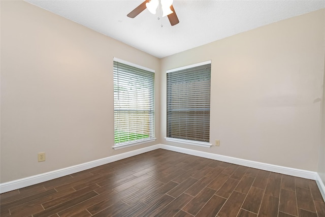 spare room with a ceiling fan, baseboards, and dark wood finished floors