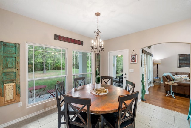 dining space featuring arched walkways, baseboards, an inviting chandelier, and light tile patterned floors