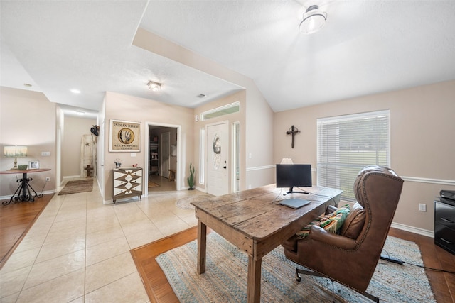 office area featuring baseboards, vaulted ceiling, and light tile patterned flooring