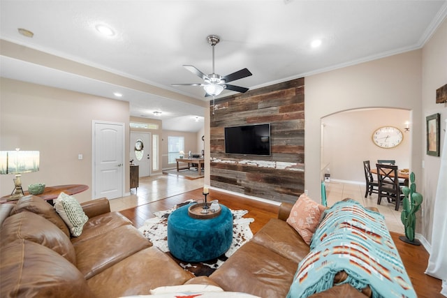 living area featuring wooden walls, arched walkways, a ceiling fan, recessed lighting, and ornamental molding