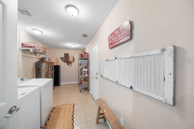 washroom with independent washer and dryer, a textured ceiling, visible vents, and light tile patterned floors