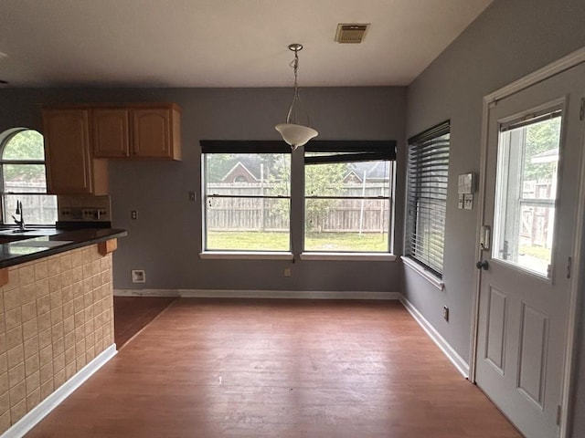 unfurnished dining area with visible vents, wood finished floors, and a wealth of natural light