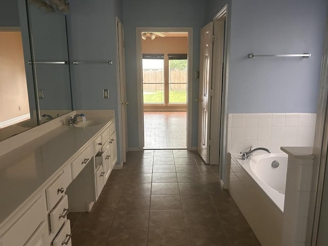 bathroom featuring vanity, baseboards, tile patterned floors, and a bath