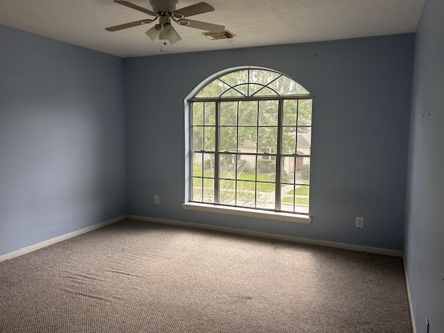 carpeted spare room with ceiling fan, visible vents, and baseboards