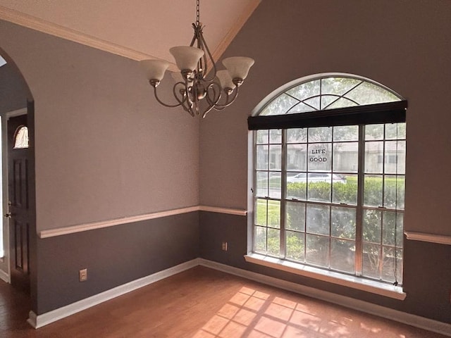 unfurnished dining area with arched walkways, baseboards, wood finished floors, and a notable chandelier