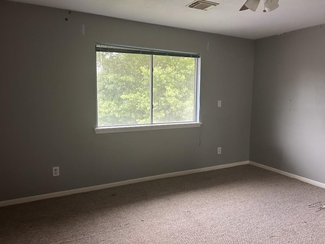 unfurnished room featuring visible vents, carpet floors, a wealth of natural light, and ceiling fan