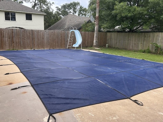 view of pool with a fenced in pool, a fenced backyard, and a water slide