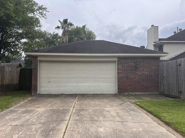 garage with concrete driveway and fence