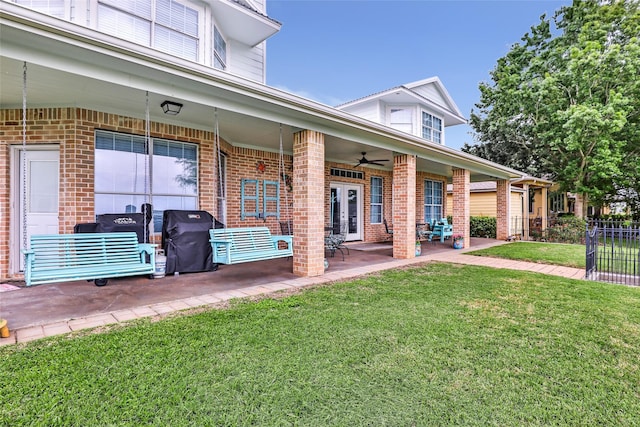 exterior space featuring french doors, a ceiling fan, a yard, and brick siding