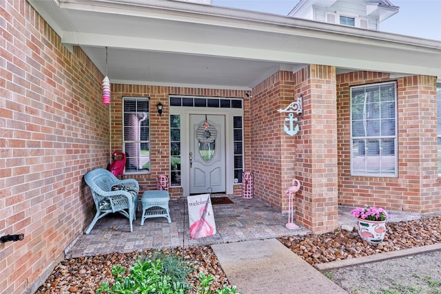 property entrance featuring a porch and brick siding