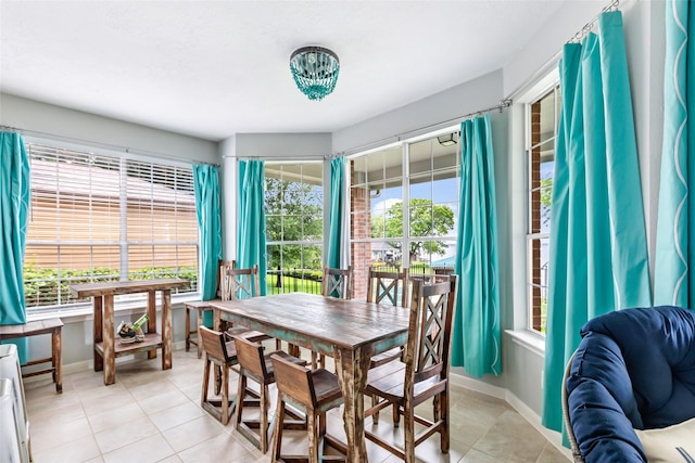 dining room featuring baseboards, a chandelier, and light tile patterned flooring