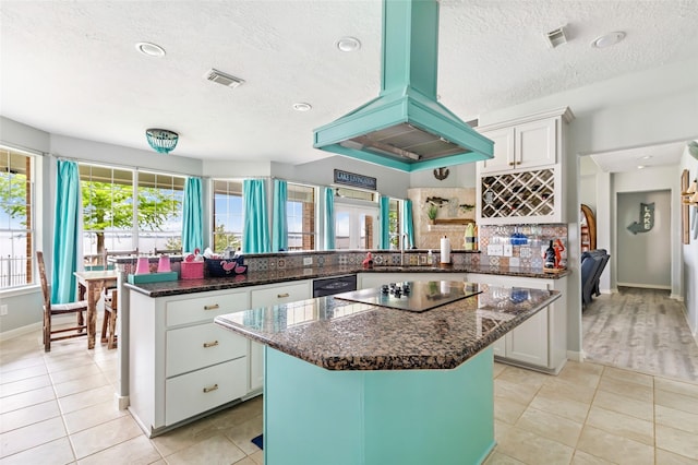 kitchen with visible vents, a peninsula, a textured ceiling, white cabinetry, and ventilation hood