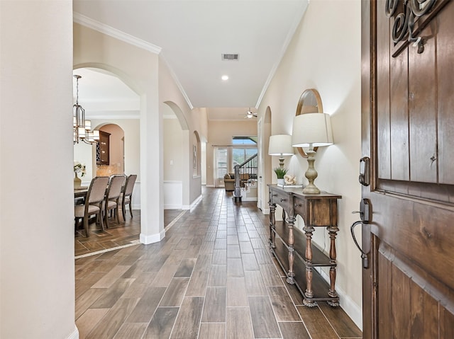 foyer featuring arched walkways, baseboards, visible vents, and ornamental molding