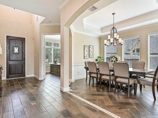 dining space with visible vents, baseboards, a raised ceiling, a chandelier, and ornamental molding