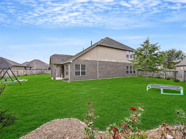 rear view of house featuring a lawn, brick siding, and a fenced backyard