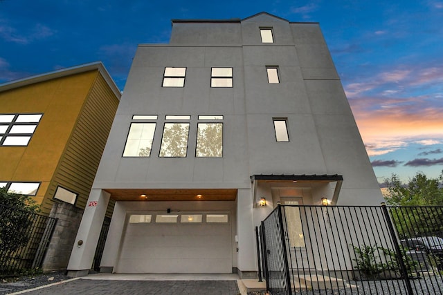 2303 Yupon St, Houston, TX 77006 - contemporary house featuring an attached garage, fence, stucco siding, and driveway