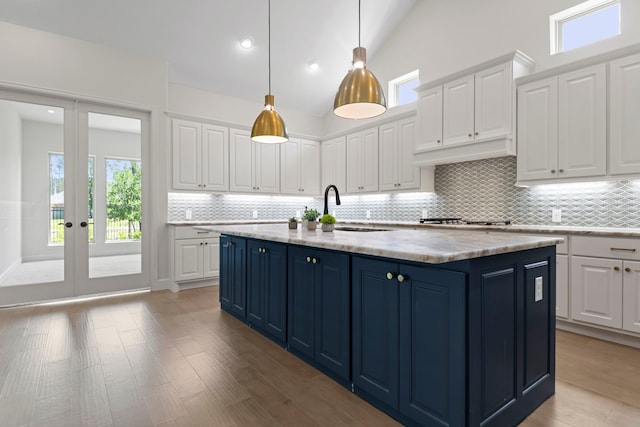 21873 Otter Point Ln, Porter, TX 77365 - kitchen featuring white cabinets, a sink, stainless steel gas cooktop, decorative backsplash, and blue cabinets