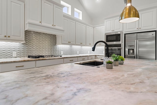 21873 Otter Point Ln, Porter, TX 77365 - kitchen featuring light stone countertops, white cabinets, a sink, appliances with stainless steel finishes, and backsplash