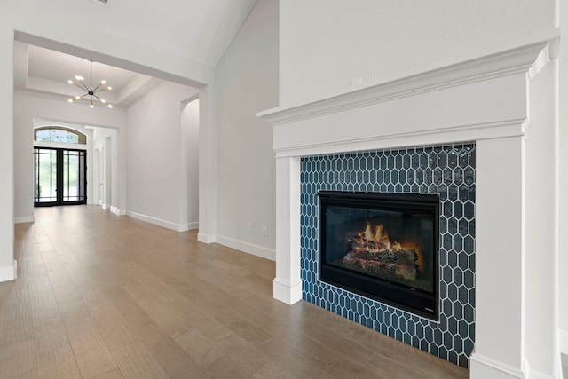 21873 Otter Point Ln, Porter, TX 77365 - interior space featuring an inviting chandelier, a tiled fireplace, baseboards, wood finished floors, and a tray ceiling