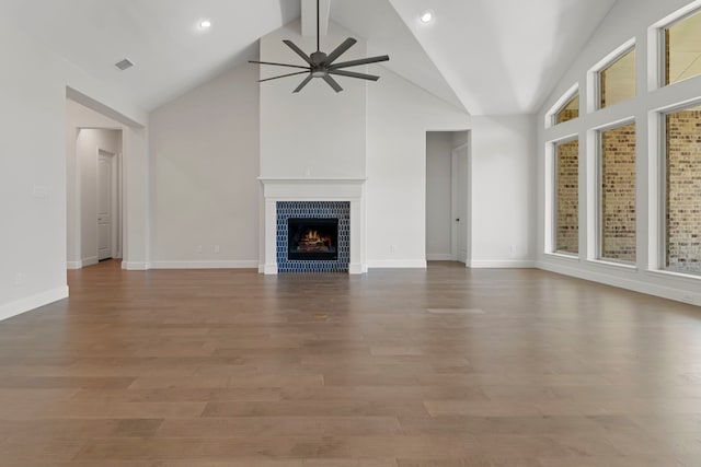 21873 Otter Point Ln, Porter, TX 77365 - unfurnished living room featuring a tiled fireplace, ceiling fan, wood finished floors, and visible vents