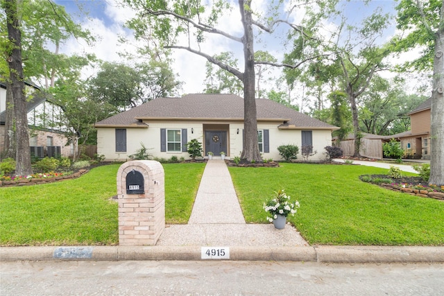 single story home featuring roof with shingles, fence, and a front yard