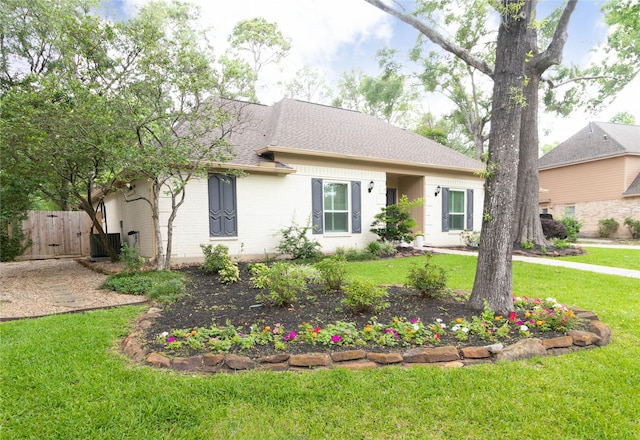 ranch-style house featuring roof with shingles, a gate, a front lawn, and brick siding