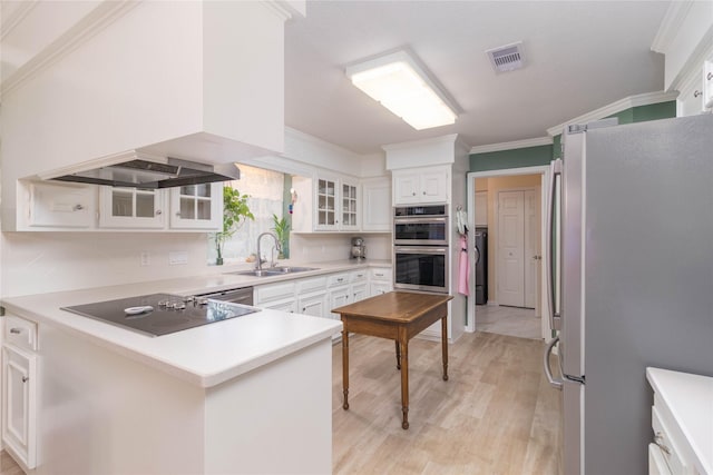 kitchen featuring a sink, light wood finished floors, stainless steel appliances, white cabinetry, and a peninsula