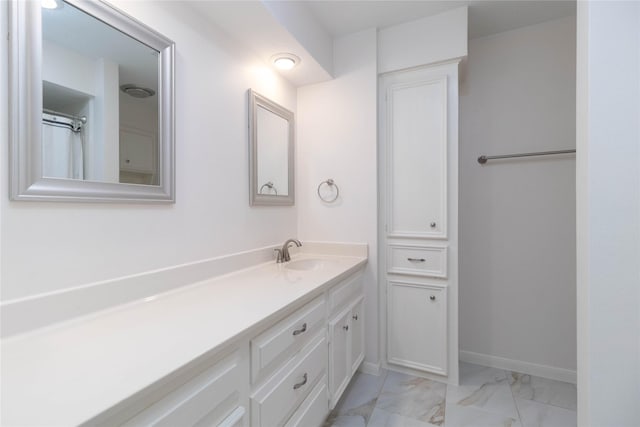 full bath with vanity, baseboards, and marble finish floor