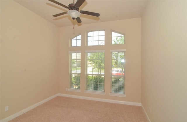 carpeted empty room featuring baseboards and ceiling fan