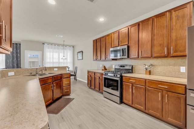 23134 Quiet Heron Ct, Katy, TX 77493 - kitchen with appliances with stainless steel finishes, a sink, brown cabinets, light countertops, and plenty of natural light