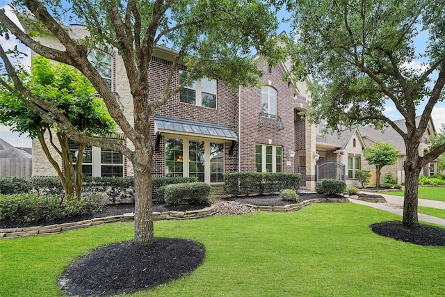 view of front of property featuring a standing seam roof, a front yard, and brick siding