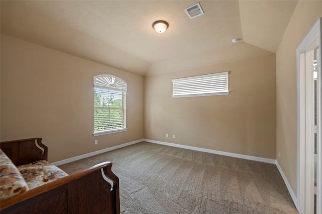 carpeted bedroom with baseboards, vaulted ceiling, and visible vents