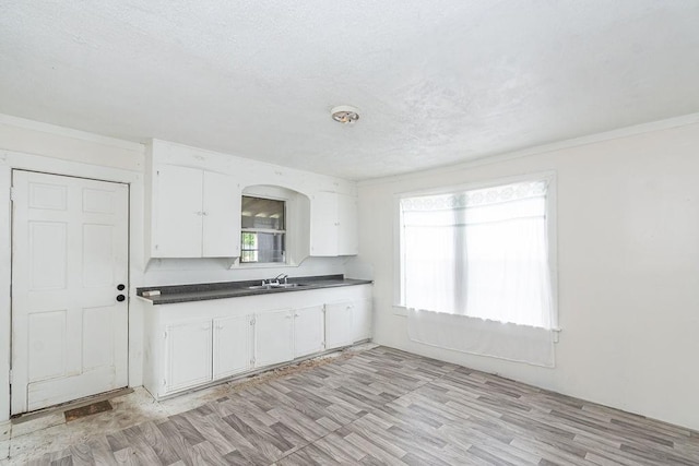 1817 Mcdaniel St, Houston, TX 77093 - kitchen with light wood-style floors, a sink, white cabinets, and dark countertops